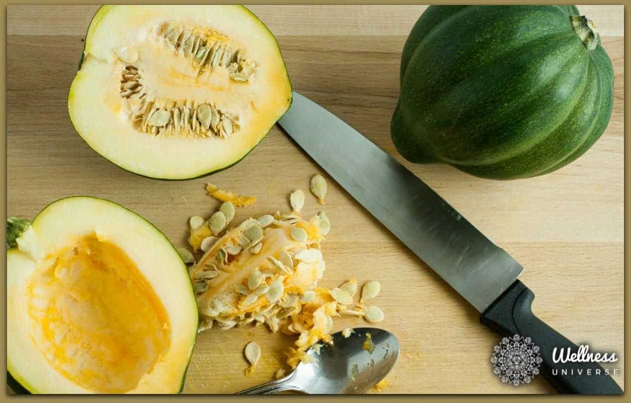 Image displaying two whole acorn squashes, with one of them cut into two halves. A fork and knife are also placed nearby, ready for preparation