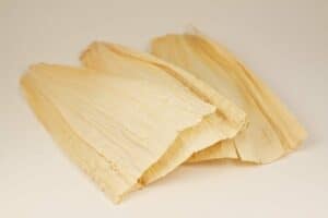Corn husks neatly arranged, representing a traditional and natural wrapping material for tamales and other dishes