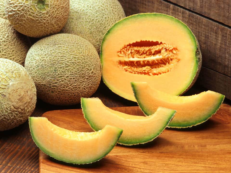 close-up of several Cantaloupes, cut in half and arranged on a wooden surface